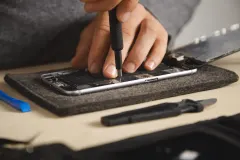 Майстер iFixit розбирає смартфон на робочому столі, досліджуючи гнучкий дисплей та шарнірний механізм.